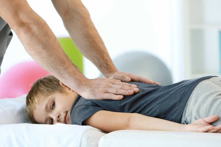 Adult discussing back pain and treatment frequency with a chiropractor in a bright examination room.